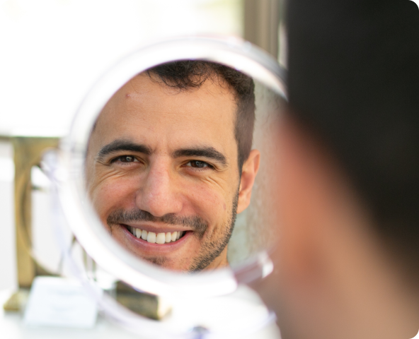 Man looking in the mirror admiring his hair after a successful FUE hair transplant